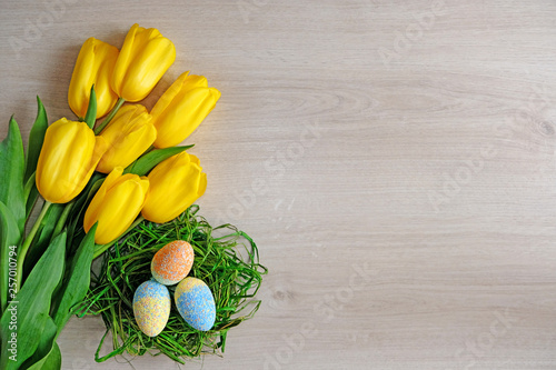  colorful Easter eggs in a nest with a bouquet of spring flowers