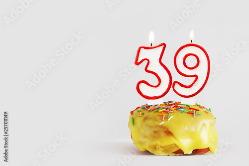 Thirty nine years anniversary. Birthday cupcake with white burning candles with red border in the form of number Thirty nine. Light gray background with copy space photo