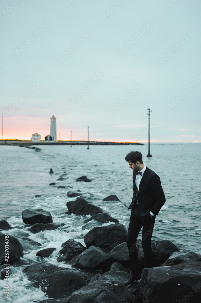 Man in the suit by the sea next to the lighthouse