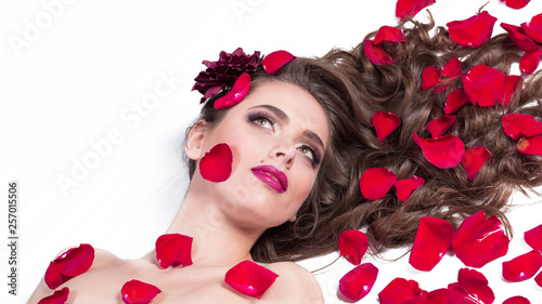 beautiful young woman lying among rose petals