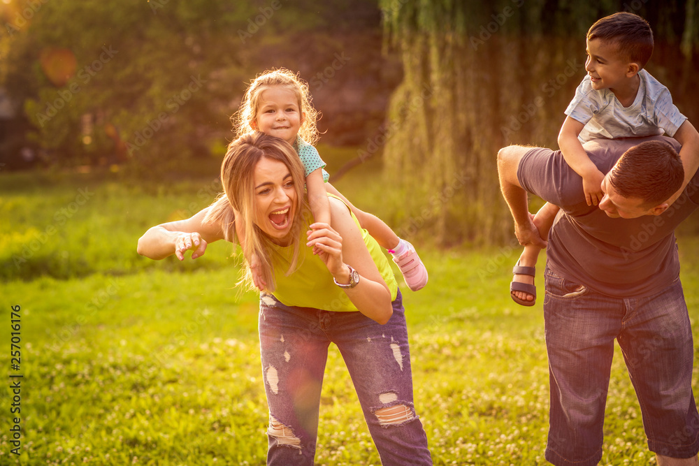 Fototapeta premium Zabawny czas - Rodzice podjeżdżają dzieciom na barana.