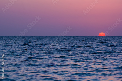 Amazing sea sunset on the pebble beach, the sun, waves, clouds