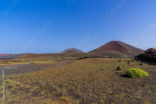 Spain, Lanzarote, Majestic red volcano mountains of timanfaya landscape behind green hills