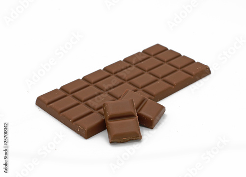 Milk chocolate bar and chocolate pieces isolated on white background