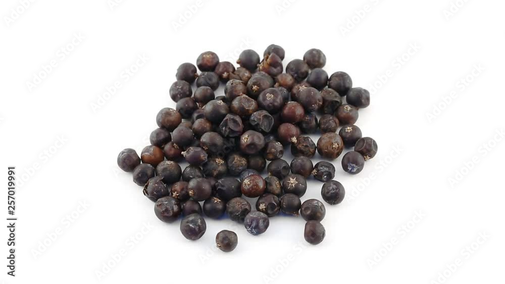 Pile of juniper berries rotating on white background top view - juniper berries are used as seasoning in the kitchen