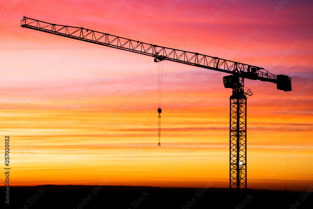 The silhouette of crane on the background of beautiful scarlet sunrise or sunset with cloudy sky colored in red, rose, scarlet, purple and blue vivid colores The silhouette of crane on the background of beautiful scarlet sunrise or sunset with cloudy sky colored in red, rose, scarlet, purple and blue vivid colores