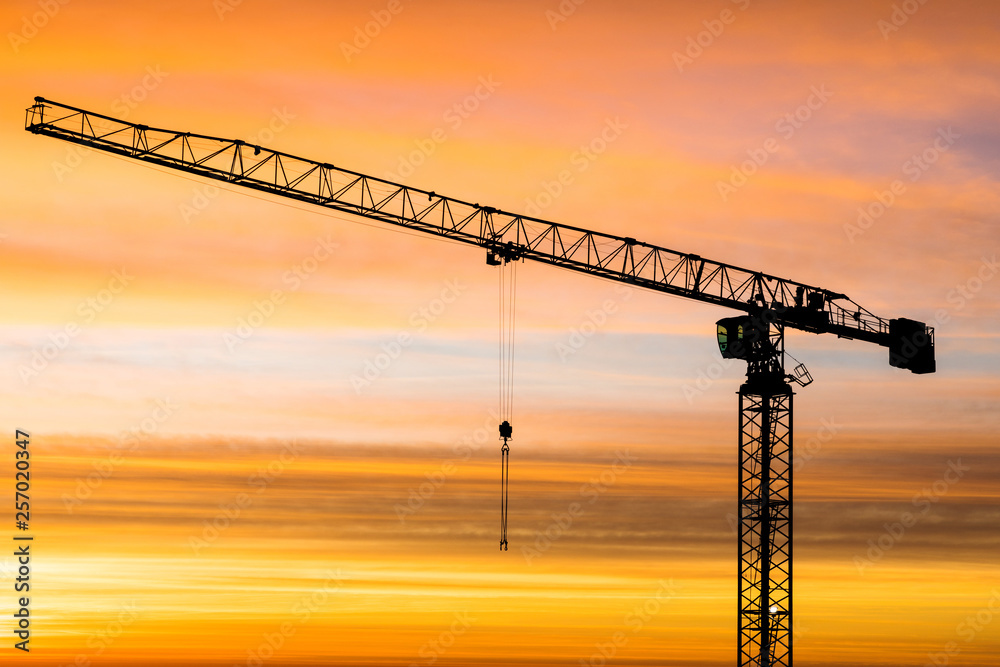 The silhouette of crane on the background of beautiful scarlet sunrise or sunset with cloudy sky colored in red, rose, scarlet, purple and blue vivid colores The silhouette of crane on the background of beautiful scarlet sunrise or sunset with cloudy sky colored in red, rose, scarlet, purple and blue vivid colores