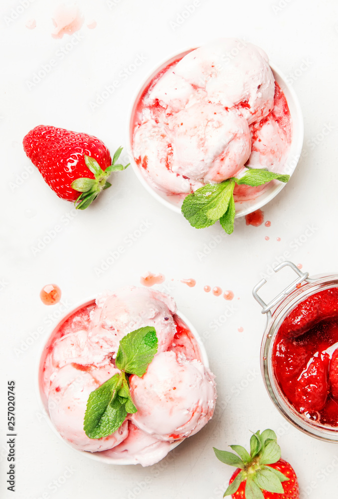 Strawberry ice cream with jam topping, decorated with green mint leaves, gray kitchen table background, top view Strawberry ice cream with jam topping, decorated with green mint leaves, gray kitchen table background, top view