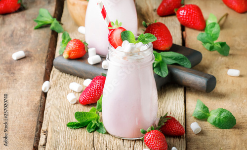 Strawberry smoothies and cocktails with fresh berry and green mint, decorated marshmallows, summer drink, wood old background, selective focus