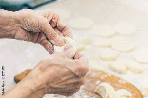 Dumplings. Dough with cabbage filling on the cook's hands.