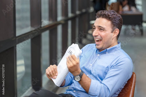 Businessman reading newspaper over office building. Businessman happy smiling after reading goods news. Man goot a new job. photo