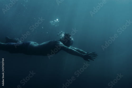 Man swimming underwater, breaststroke.