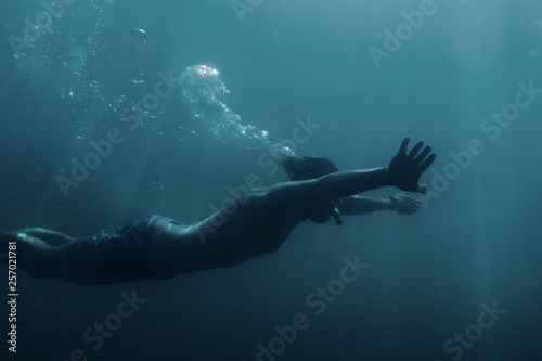 Young man swimming underwater, breaststroke.