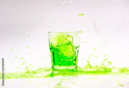 Green cocktail splash in glass isolated on white background