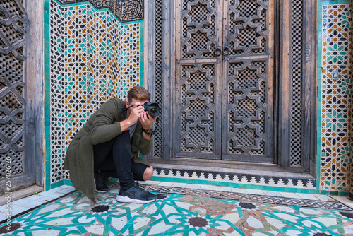 Young European tourist with a camera takes a picture in The Madrasa Bou Inania ( Medersa el Bouanania ) is acknowledged as an excellent example of Marinid architecture. Souk Medina of Fez, Fes el Bali