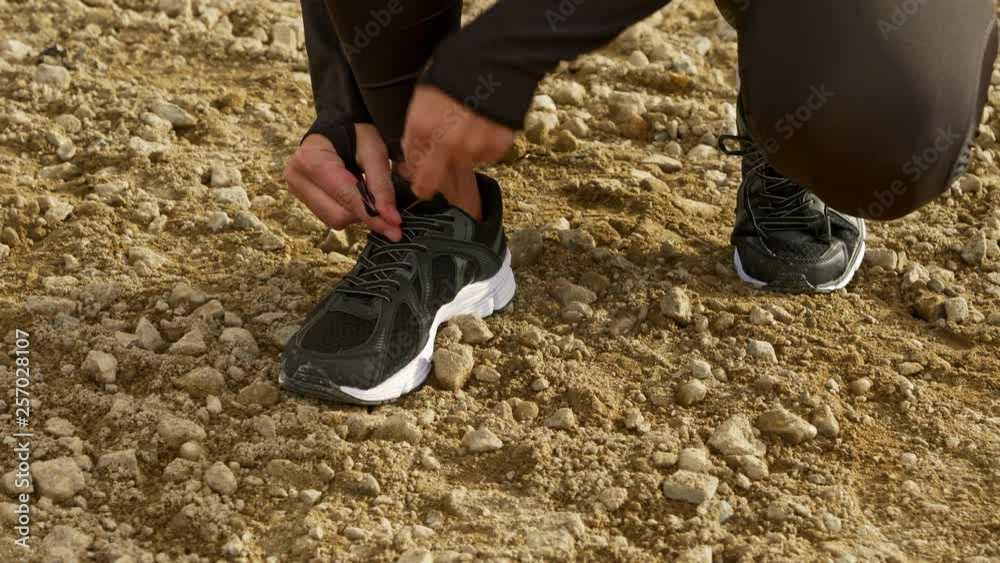 Tying shoelace on rocky ground Tying shoelace on rocky ground