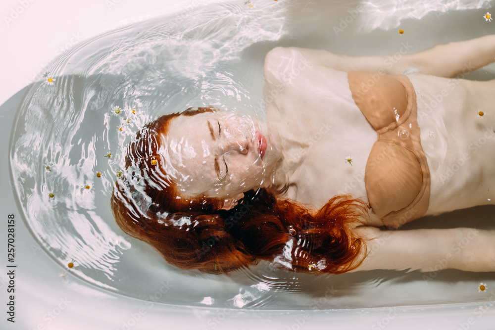 Φωτογραφία Young lady in beige bra keeps her head under the water trying to get free her mind of the psychological strains and stress