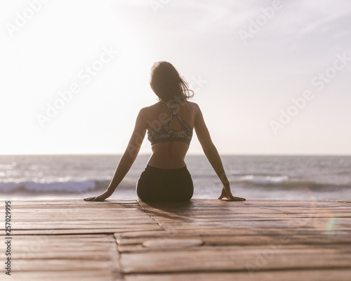 Young woman relaxing on the beach before yoga at sunset