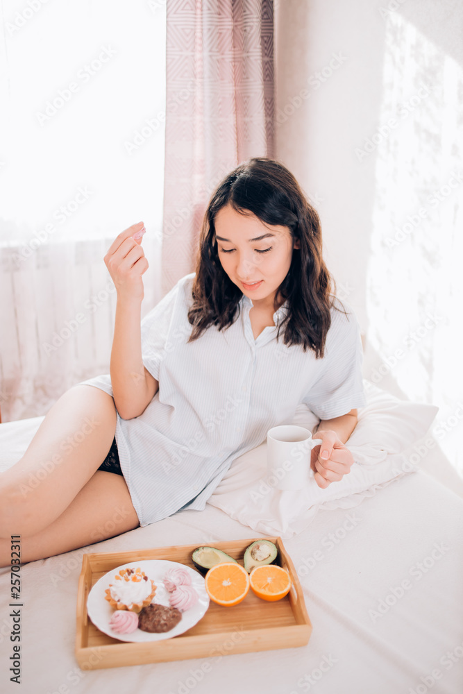 Young woman eating healthy breakfast in bed