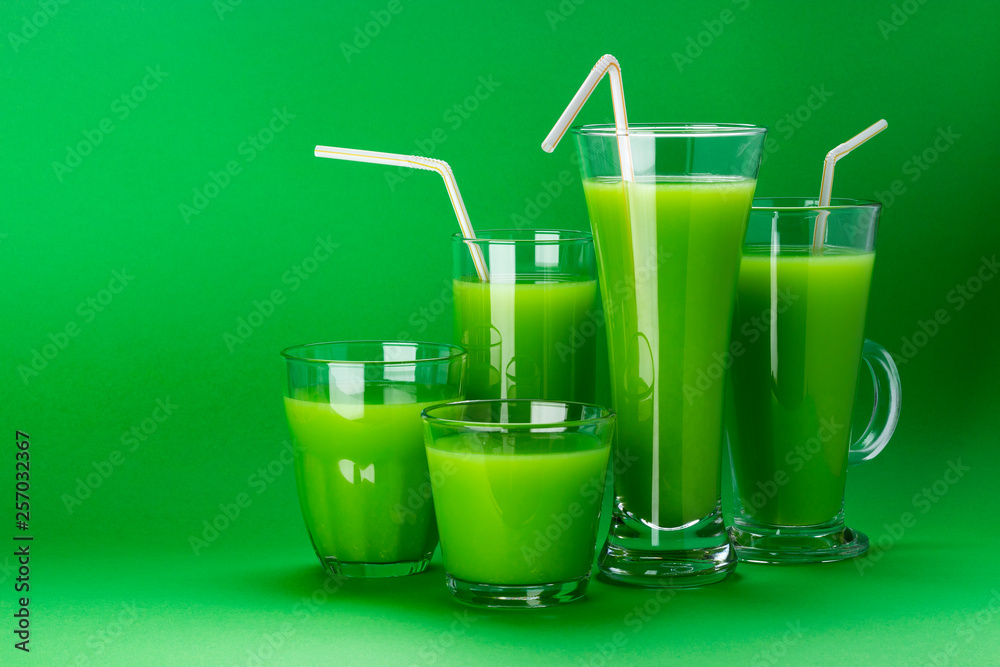 Glasses of green juice isolated on colour green background with copy space for text, fresh apple and celery cocktail