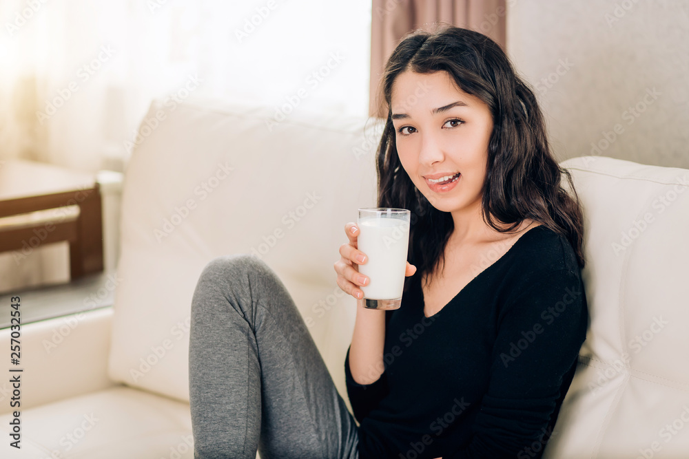 Beautiful young woman with glass of milk at home