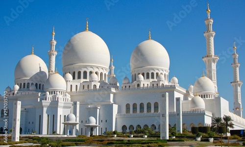 The Famous Abu Dhabi Grand Mosque during the day showing the minarets, spires, and centre dome on a beautiful blue sky day