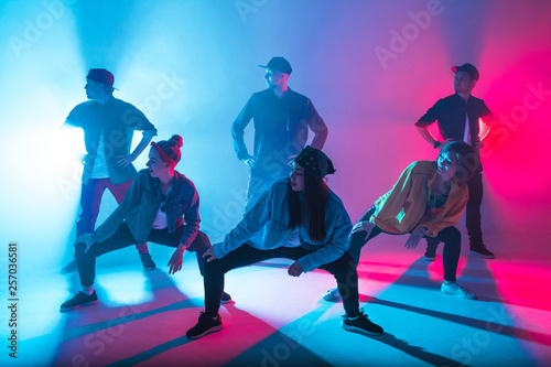 Photo Group of diverse young hip-hop dancers in studio with special lighting effects i