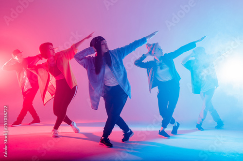 Fototapeta Naklejka Na Ścianę i Meble -  Group of male and female dancers in colorful neon light having fun dancing. Party guests enjoy atmosphere and effects in the night club. Creative fashionable neon color.