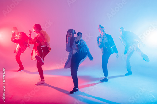 Fototapeta Group of diverse young hip-hop dancers in studio with special lighting effects i