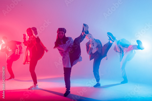 Fototapeta Naklejka Na Ścianę i Meble -  Animation group of young women and men dancing over red and blue dual color light on dark background