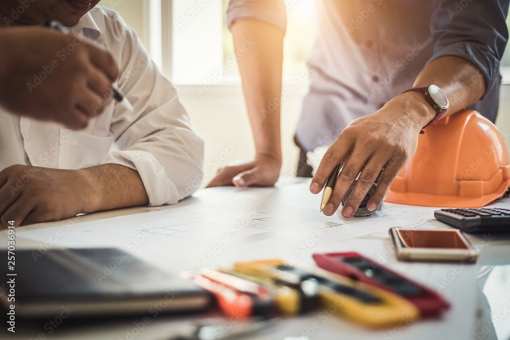 Engineer working at a blueprint of house in office for discussing real estate project. Engineering tools and construction concept. Engineer working at a blueprint of house in office for discussing real estate project. Engineering tools and construction concept.