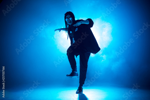 Stylish woman dancing solo on hip hop party. Sunglasses, modern black dance wear, neon lights.