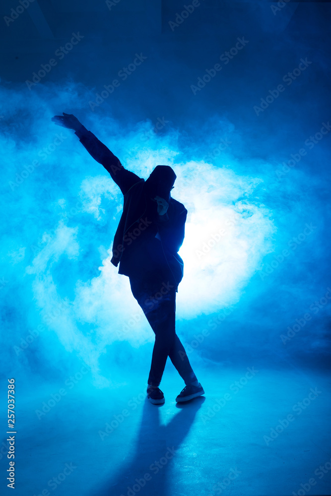 Full-size of silhouette of male break dancer performing on blue neon stage his expressive dance, Dark blue background with light flare on background