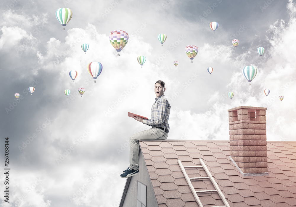 Handsome student guy reading book and aerostats flying in air Handsome student guy reading book and aerostats flying in air