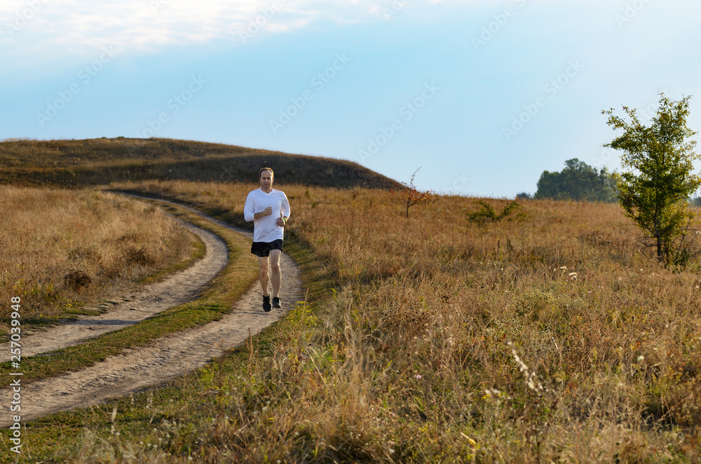 Middle age man running alone outdoors countryside at fall