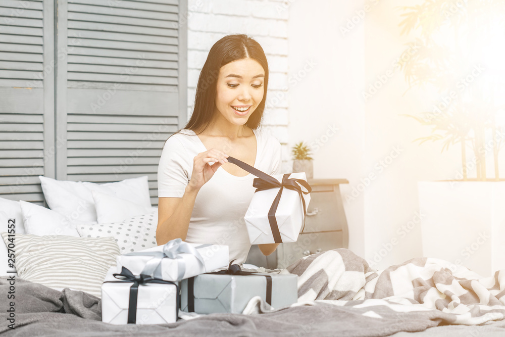Smiling happy beautiful woman with gift boxes lying in bed. Morning surprise. Packing gifts. Online shopping. Smiling happy beautiful woman with gift boxes lying in bed. Morning surprise. Packing gifts. Online shopping.