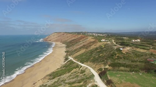 Wide Aerial View of Two Paraglider Soaring Beach Cliff