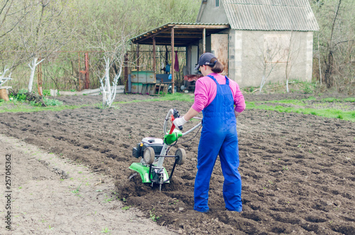 Young girl working in a spring garden with a cultivator