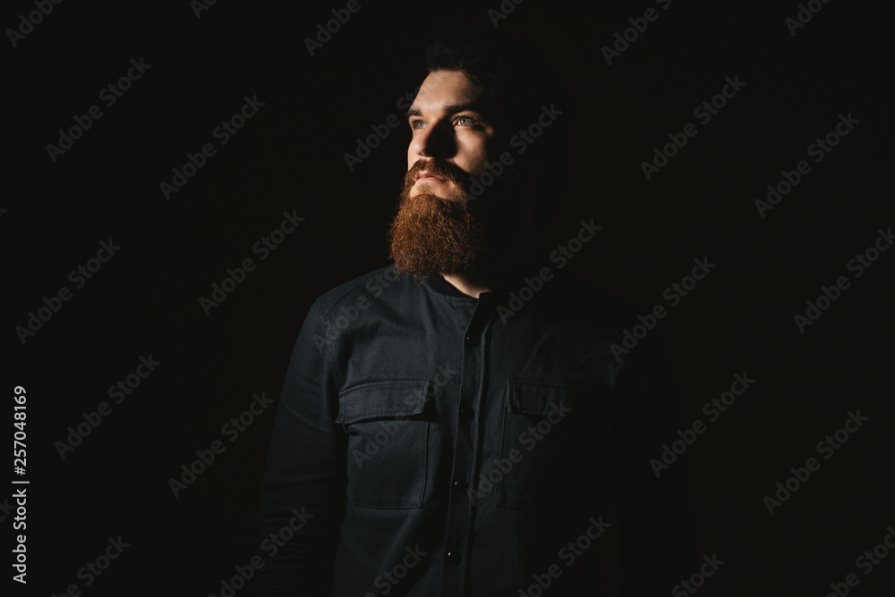 Close-up portrait of a handsome serious young man over dark background. Male beauty. Men's health.