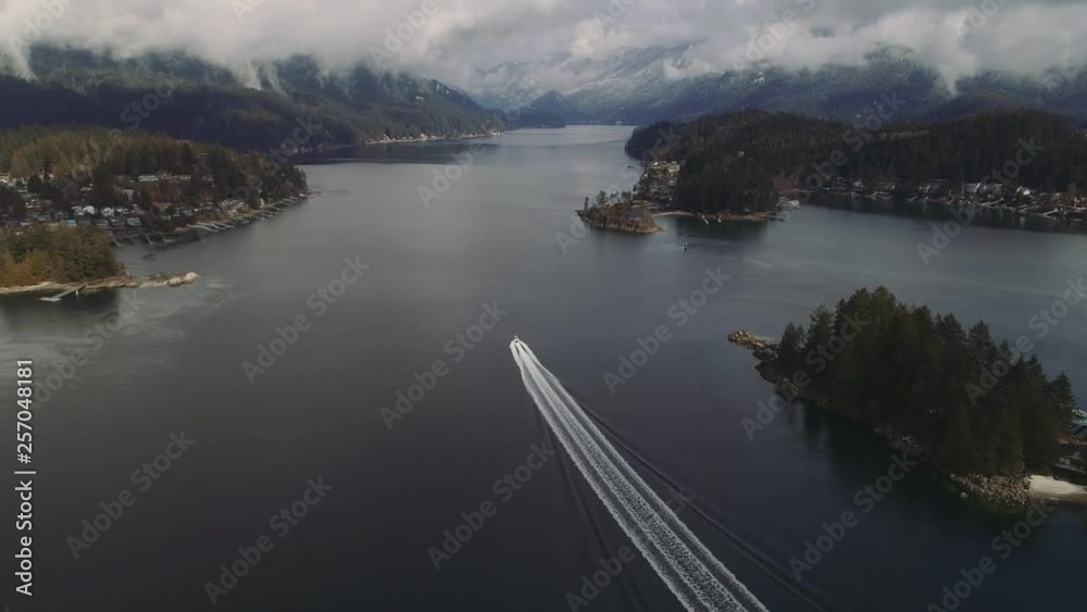 Gorgeous aerial shot following speedboat through fjord in Canada. Fog/clouds and houses along coastline. Epic view. Gorgeous aerial shot following speedboat through fjord in Canada. Fog/clouds and houses along coastline. Epic view.