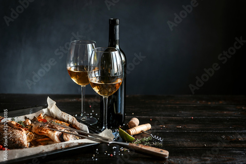 Foto dinner concept for two. two glasses of white wine, baked fish.