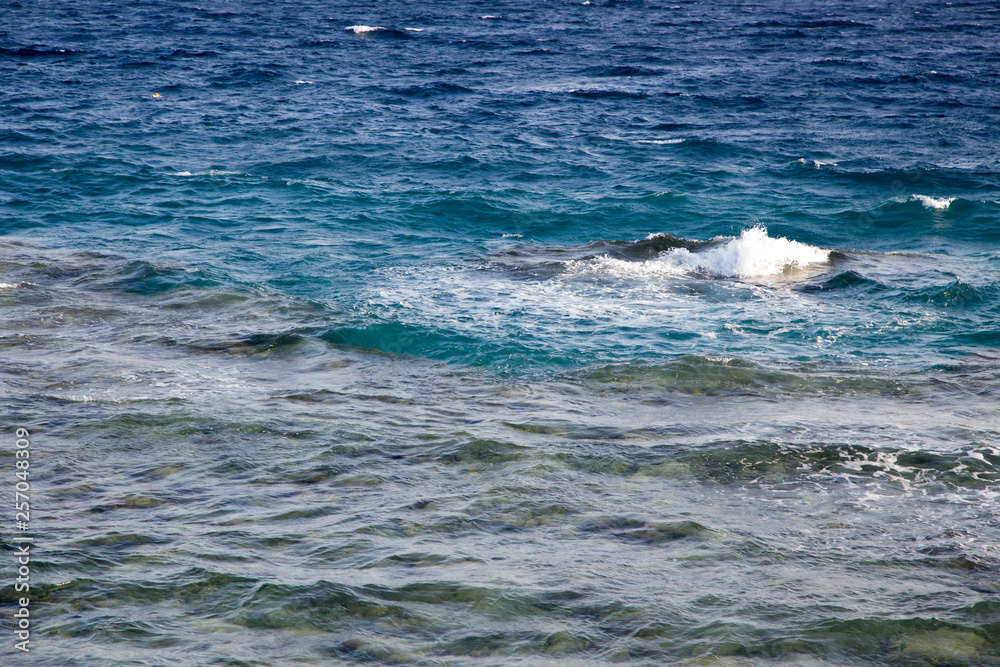 Fototapeta premium Waves in the ocean. Beautiful blue sea wave photograph close up. Beach vacation at sea or ocean. Background to insert images and text. Tourism, travel.