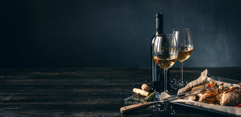 dinner concept for two. two glasses of white wine, baked fish.