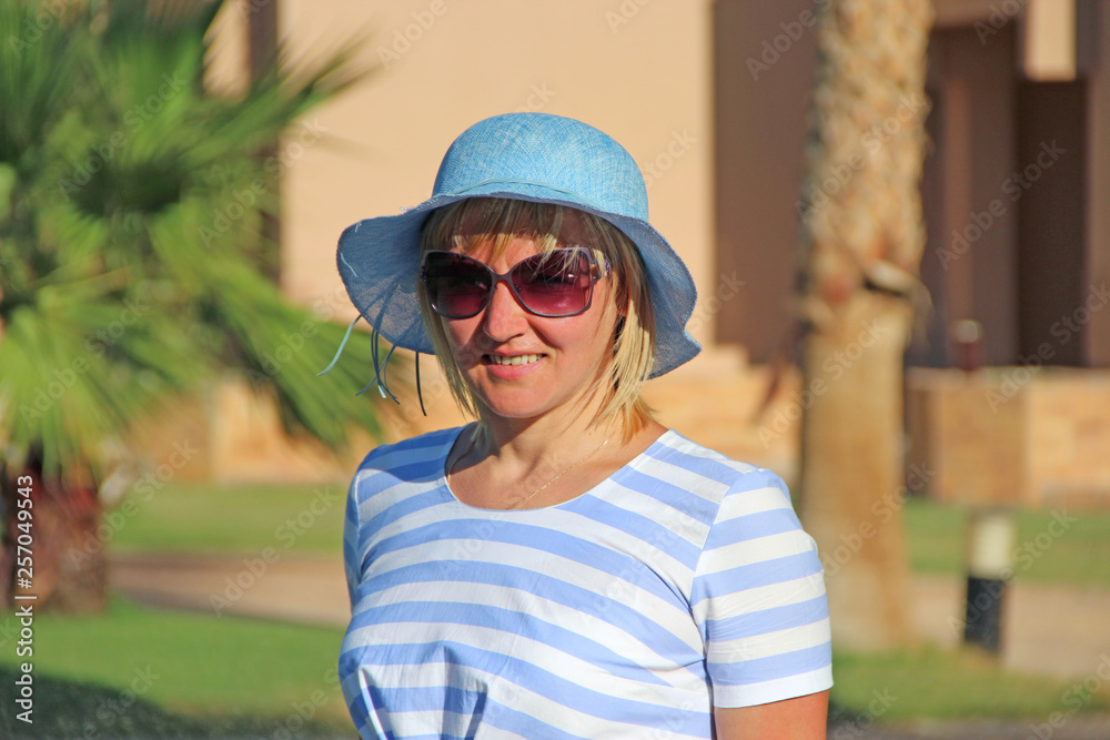 Fashionable woman in pink hat enjoying walking along park. Attractive girl