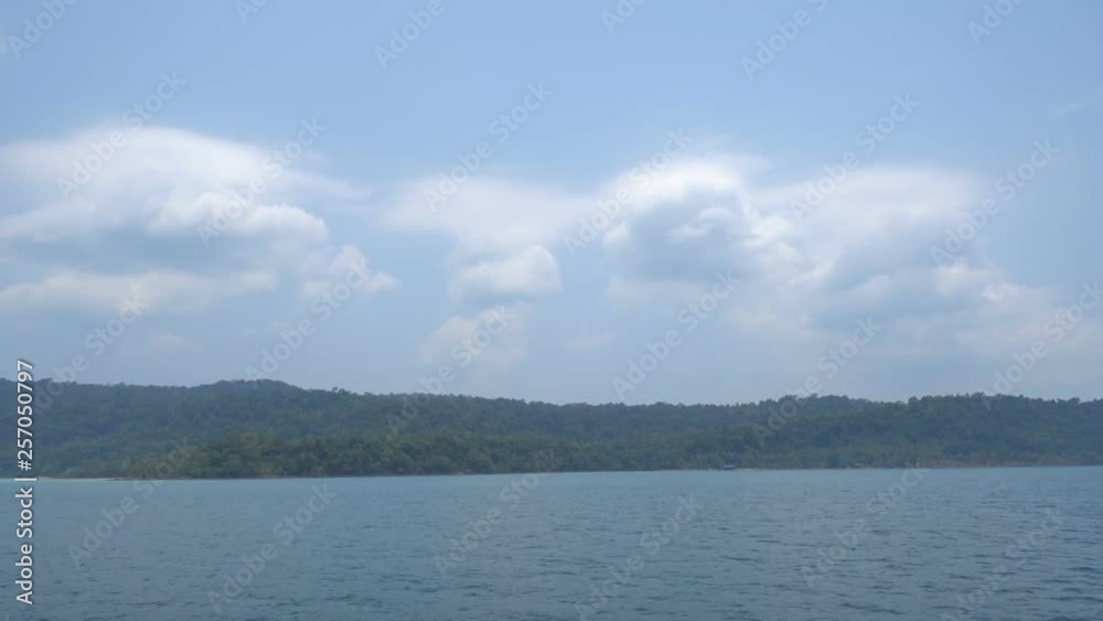 Lush island on a remote destination with calm blue seas and billowing clouds in the background. Lush island on a remote destination with calm blue seas and billowing clouds in the background.