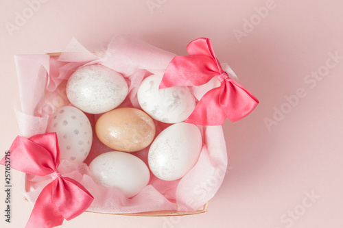 White Easter eggs in a nest on pink background. Design pastel tone in minimal flat lay