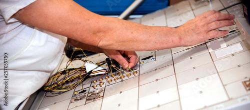 Obraz na płótnie Hands of an employee who tests a part of the wiring for cars at a modern plant at a special stand in the production shop w salonie