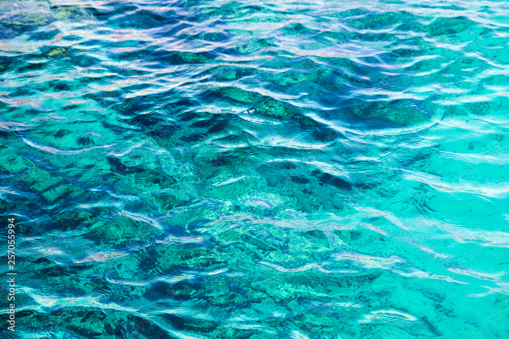 Coral reef is visible through the clear blue water. Beautiful blue sea wave photograph close up. Beach vacation at sea or ocean. Background to insert images and text. Tourism, travel. Coral reef is visible through the clear blue water. Beautiful blue sea wave photograph close up. Beach vacation at sea or ocean. Background to insert images and text. Tourism, travel.