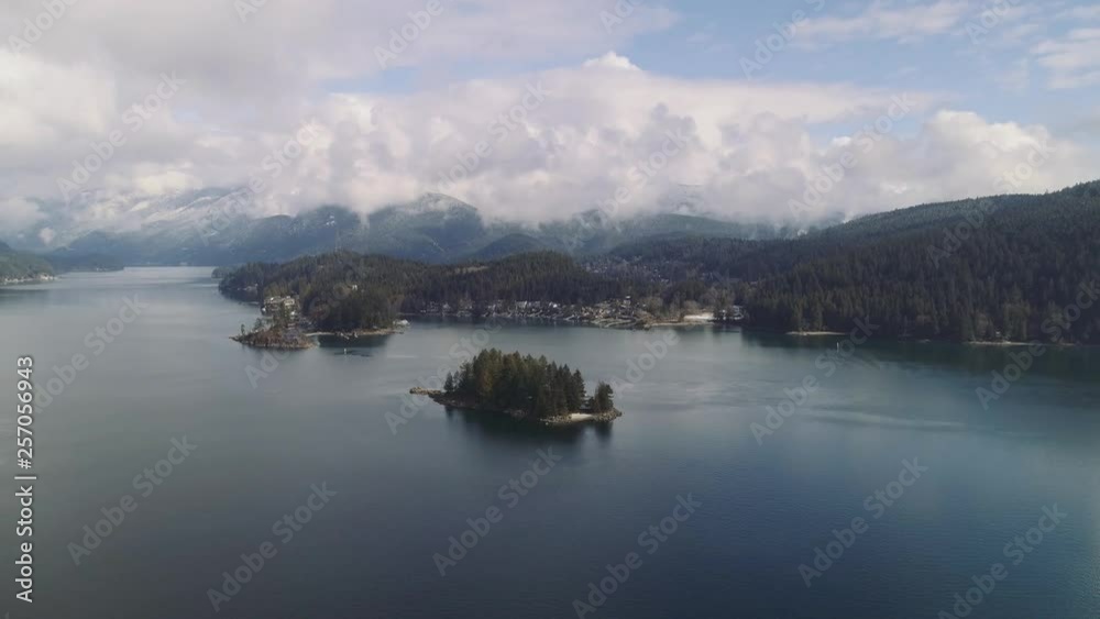 Aerial shot flying over water towards forest coast with houses in Canada. Near Vancouver, beautiful clouds. Aerial shot flying over water towards forest coast with houses in Canada. Near Vancouver, beautiful clouds.
