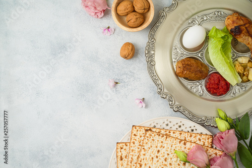 Jewish holiday Passover background with matzo, seder plate and spring flowers.